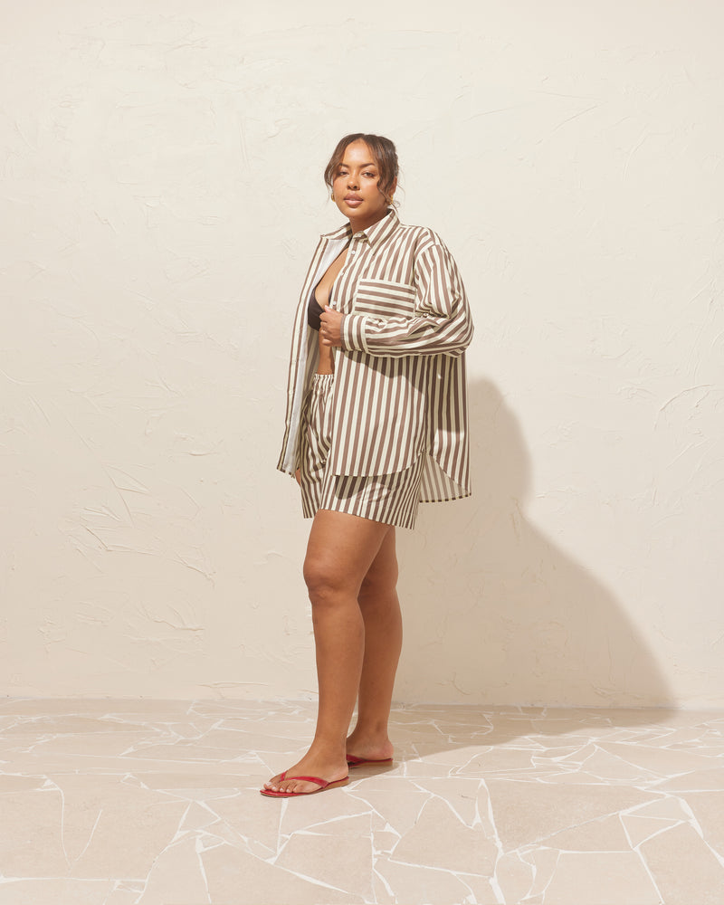 IDA SHIRT BROWN BUTTER STRIPE | Relaxed crisp shirt with classic shirt detailing and a large contrast stripe pocket, designed in brown butter striped organic cotton. This piece is a timeless wardrobe staple that you will...