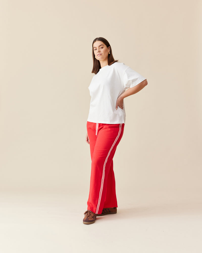 CORVETTE TROUSER RED PINK | A new take on the an all-time RUBY favourite. The Corvette Trouser is now available in a two-tone version. Sporty, high-waisted pant with a wide-leg silhouette. The stripe on the...