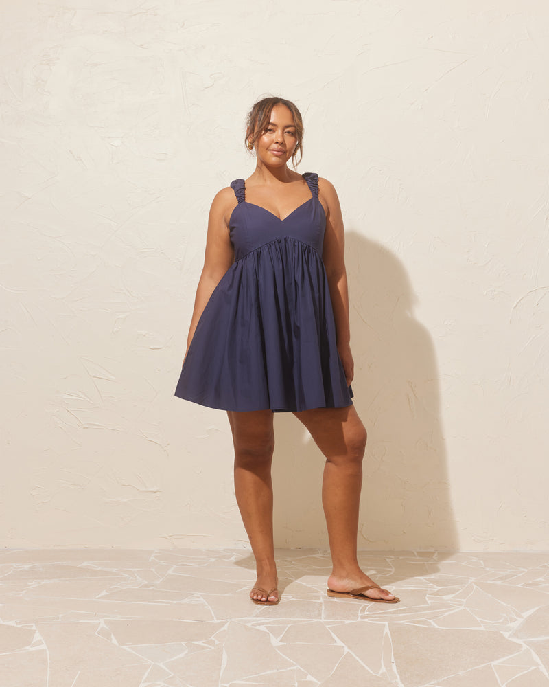 MARNIE MINIDRESS NAVY | Babydoll mini dress designed in a crisp navy cotton. This dress features 'puff' ruched straps and bust detailing that falls to an A-line gathered mini skirt.