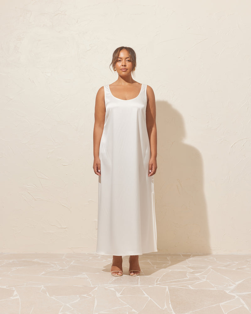 SIMONA SLIP DRESS WHITE | Satin slip dress with a scooped neckline and wide straps. This dress has a loose silhouette and feels luxe to wear