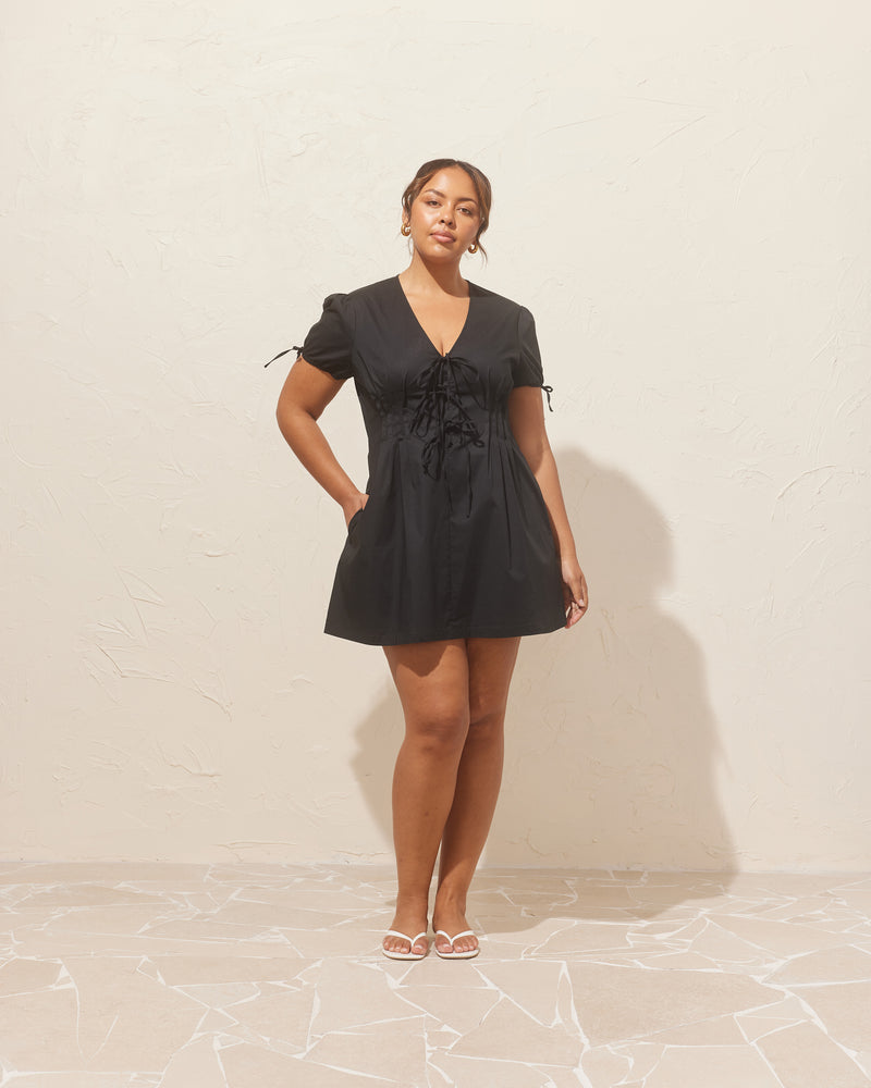 SIMONA MINI DRESS BLACK | Short-sleeve cotton mini dress, designed with pleating and a tie front closure. Simple and sweet, this dress has a bit of stretch to ensure a good fit and a placket...