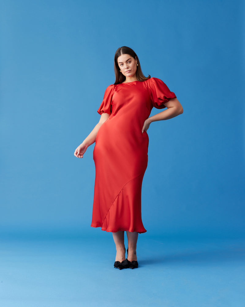 KENDALL SATIN DRESS CHILLI | Bias cut satin midi dress with puff sleeves and a keyhole button closure at the back neck. The bias silhouette of this dress gently contours the body, while the chilli...