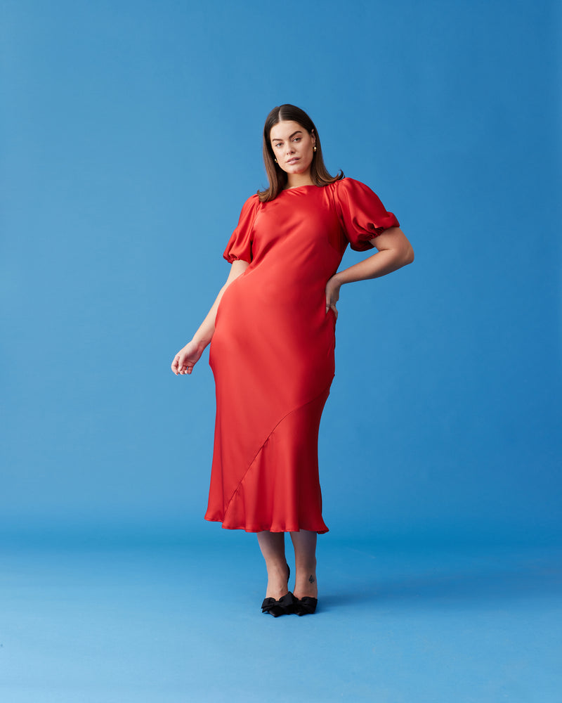 KENDALL SATIN DRESS CHILLI | Bias cut satin midi dress with puff sleeves and a keyhole button closure at the back neck. The bias silhouette of this dress gently contours the body, while the chilli...