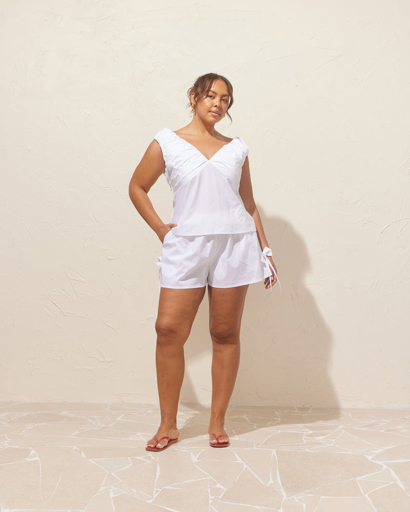 RAQUEL TOP WHITE | Crafted in a crisp white cotton with ruched detailing at the bust, this top can be worn on or off the shoulder. The tailored fit is designed to sit close...