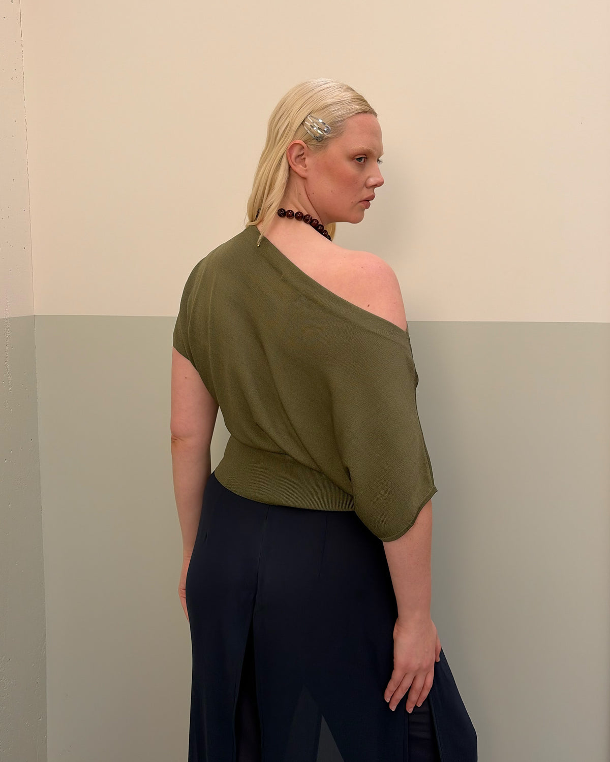 BODE BATWING SHORT SLEEVE TOP OLIVE | Off-shoulder batwing short sleeve top crafted in a mid-weight olive knit. This top is simple yet elevated and can be worn on or off the shoulder. Pair it with denim for a chic everyday look.