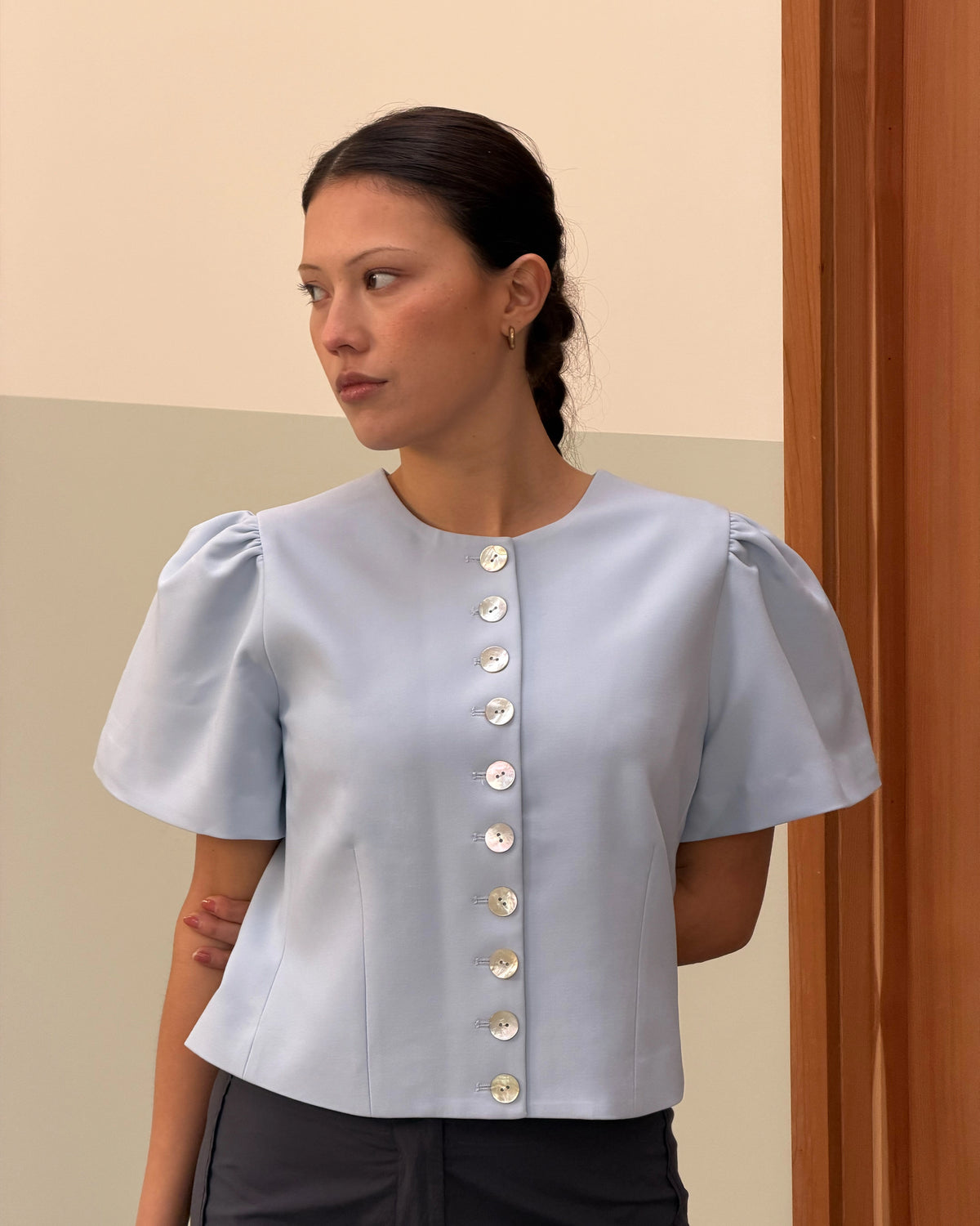 CAROLYN SHORT SLEEVE BLAZER LIGHT BLUE | Collarless short sleeve light blue blazer with feature pearlescent buttons. An elevated classic with a structured silhouette, this top is the perfect addition to your everyday workwear rotation. Pair with your favourite trousers, or denim for a more casual look.