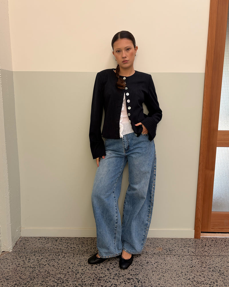 CAROLYN BLAZER NAVY PINSTRIPE | Collarless long sleeve navy pinstripe blazer with feature pearlescent buttons. An elevated classic with a structured silhouette, this top is the perfect addition to your everyday workwear rotation. Pair with the Carolyn Pant for a full suiting moment. 