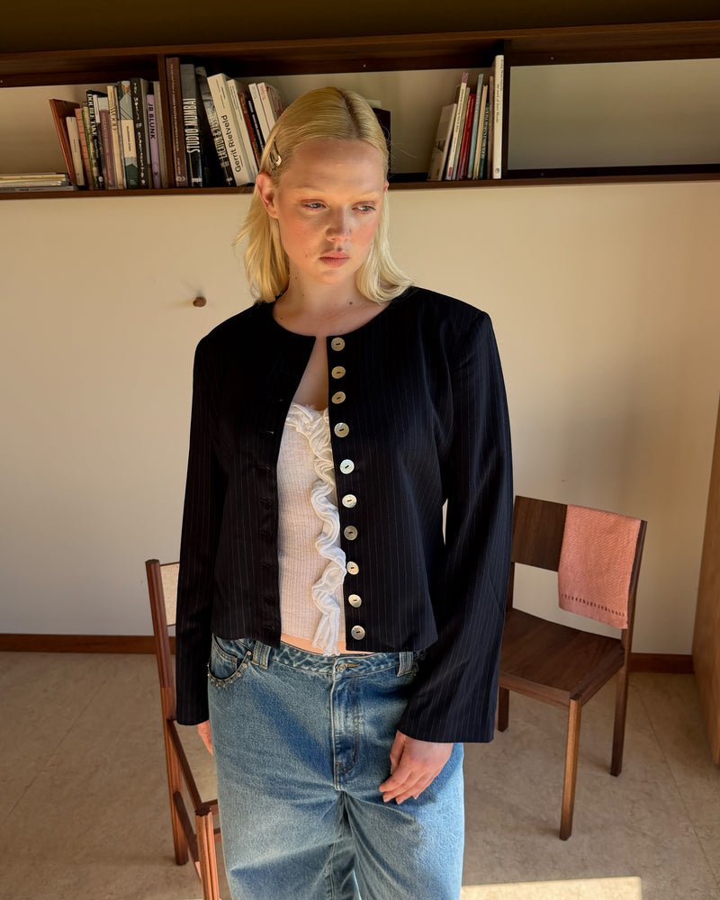 CAROLYN BLAZER NAVY PINSTRIPE | Collarless long sleeve navy pinstripe blazer with feature pearlescent buttons. An elevated classic with a structured silhouette, this top is the perfect addition to your everyday workwear rotation. Pair with the Carolyn Pant for a full suiting moment. 