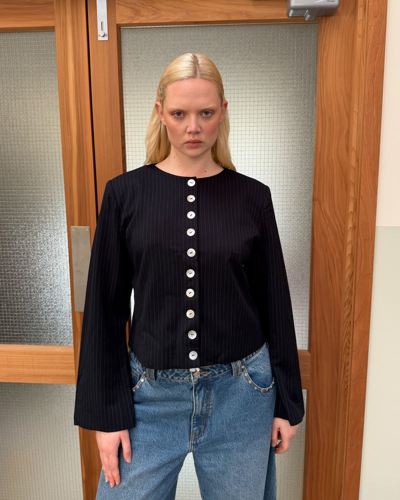 CAROLYN BLAZER NAVY PINSTRIPE | Collarless long sleeve navy pinstripe blazer with feature pearlescent buttons. An elevated classic with a structured silhouette, this top is the perfect addition to your everyday workwear rotation. Pair with the Carolyn Pant for a full suiting moment. 