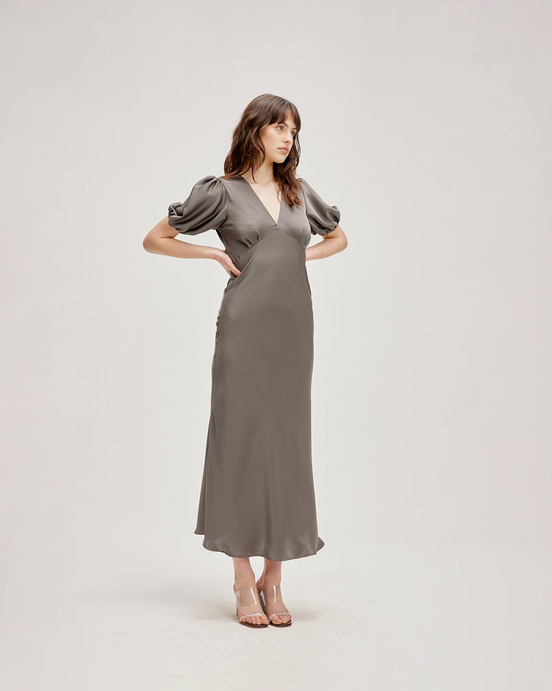 UMA SATIN DRESS CHARCOAL | Bias cut satin maxi dress with tie closure and a V-neck front and back. Back in a new luxe charcoal satin with elasticated puff sleeves and ruched detailing under the...