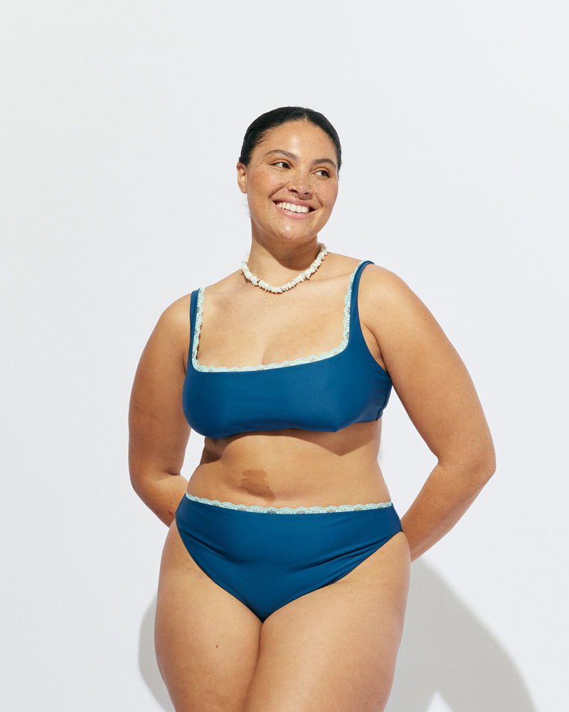 WYLIE BIKINI TANK TOP NAVY | Named after the Wylie's Baths in Sydney, this navy scoop neck bikini top is designed for higher coverage and support with a peek of aqua lace trim along the bust. With an adjustable back tie and straps for a flexible...