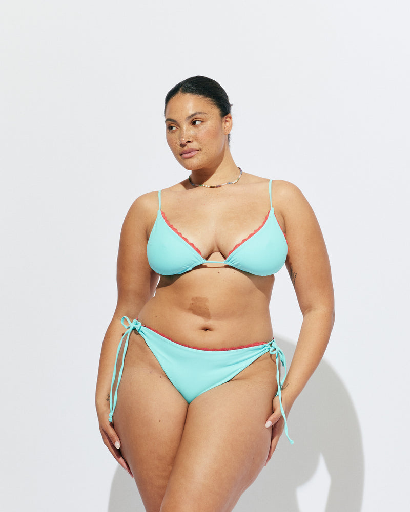 WYLIE TIE-SIDE BIKINI BOTTOM AQUA | Named after the Wylie's Baths in Sydney, these aqua bikini bottoms are designed with a cheeky cut and adjustable side ties. Featuring a bright orange contrast lace trim, make it a matching set with the Wylie Triangle Bikini Top or...