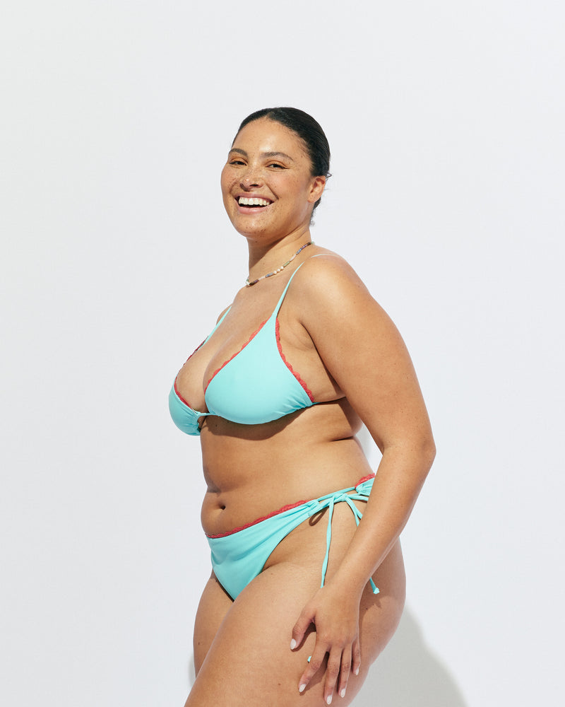WYLIE TRIANGLE BIKINI TOP AQUA | Named after the Wylie's Baths in Sydney, this aqua bikini top is designed in a classic triangle style with a feature vermillion lace trim. With adjustable ties for a flexible fit, make it a set with the Wylie Tie-side Bikini...