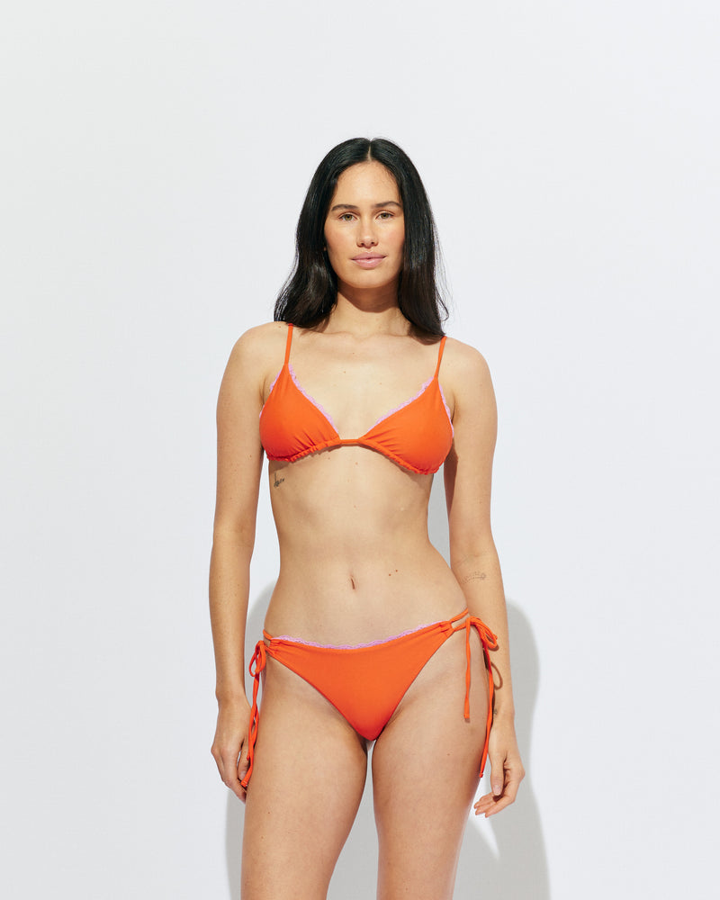 WYLIE TRIANGLE BIKINI TOP VERMILLION | Named after the Wylie's Baths in Sydney, this vermillion bikini top is designed in a classic triangle style with a vibrant pink lace trim. With adjustable ties for a flexible fit, make it a set with the Wylie Tie-side Bikini...