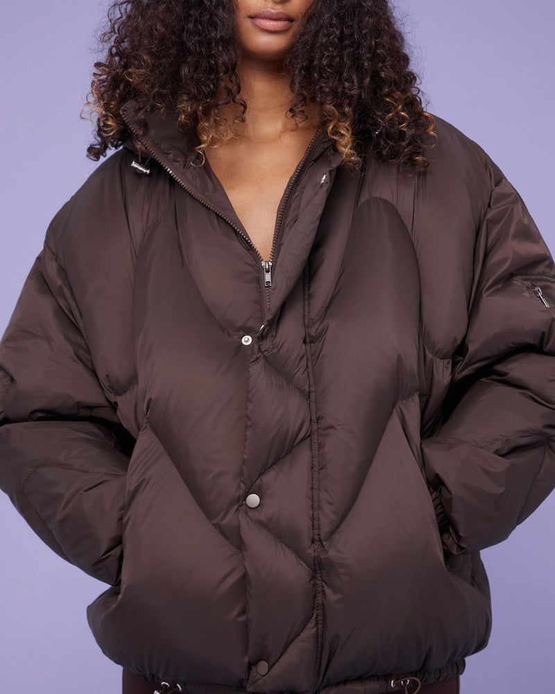 CLOUD PUFFER ESPRESSO | Quilted puffer jacket with removable hood and a stand up collar, filled with responsibly sourced down for volume and warmth. Designed for a more oversized aesthetic, this piece is bold...