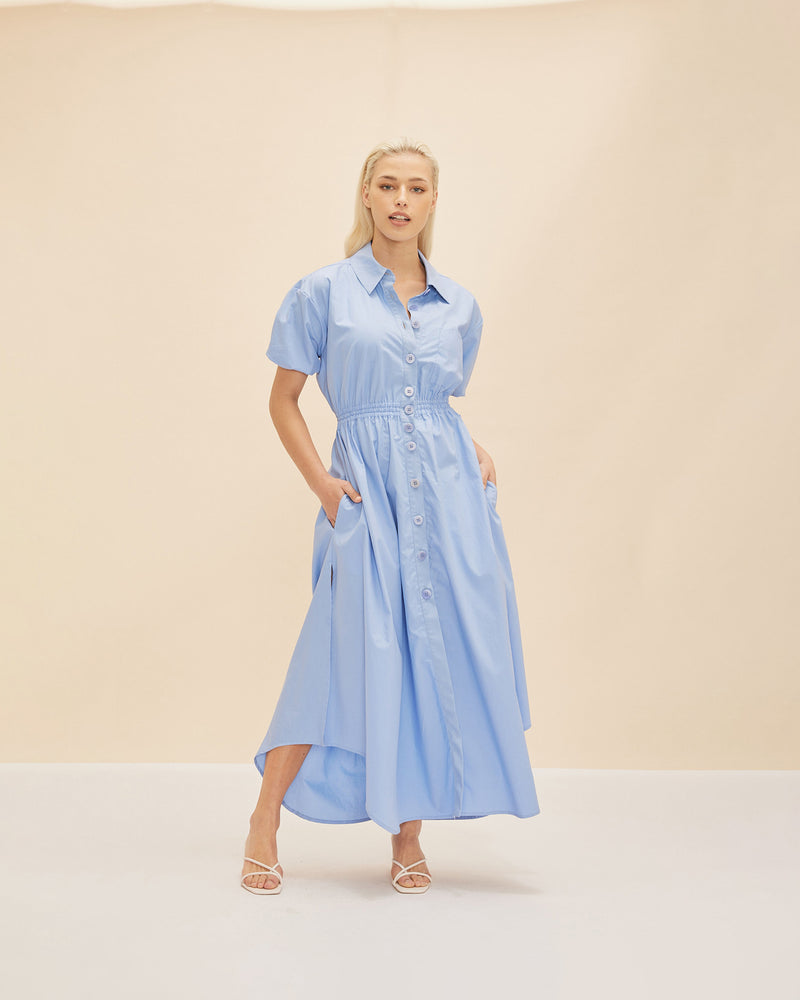 COMET SHIRT DRESS CORNFLOWER | Maxi shirt dress crafted in a cornflower blue cotton with an elasticated waist and short sleeves. The fully functional buttons allow you to show as little or as much skin...